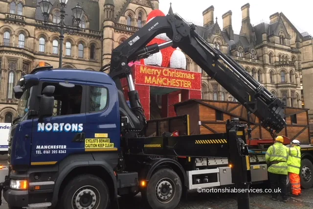 A Nortons crane lifting a timber Christmas market chalet in Albert Square Manchester