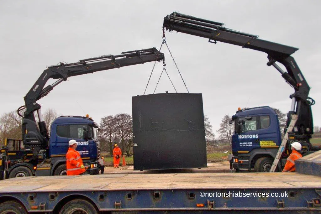 A large black fuel tank held in mid air by two Nortons lorry cranes on one lift