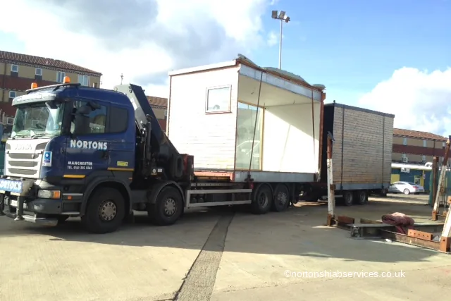 A tall open-sided modular cabin and a second unit loaded nose to tail on Nortons vehicles for a move to Hartlepool