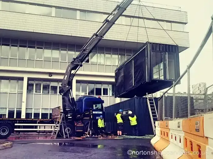 A Nortons crane lifting a glazed modular unit up alongside an office building frontage