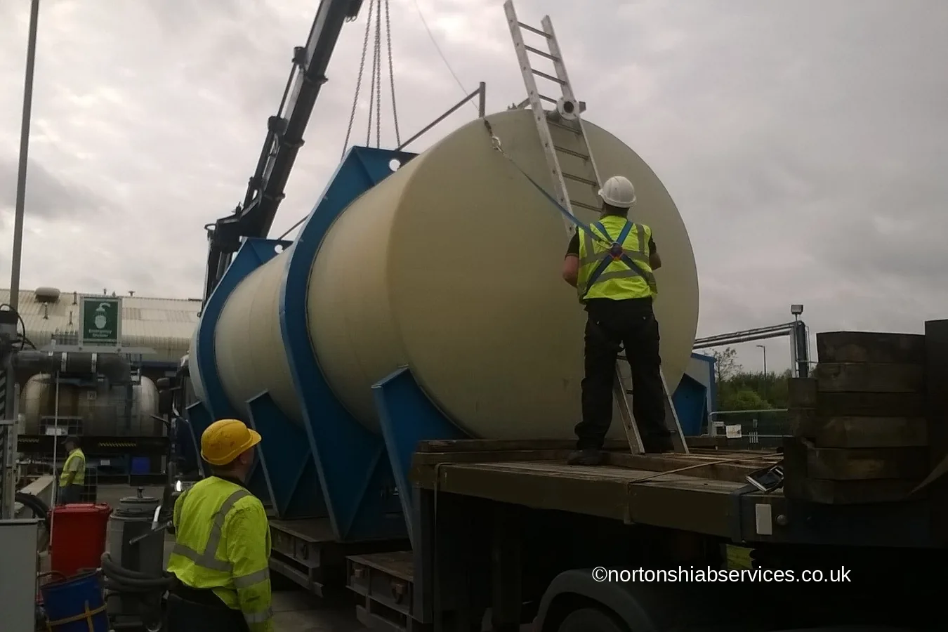 Three linked process tanks on a Nortons trailer with a man on a ladder fitting strops