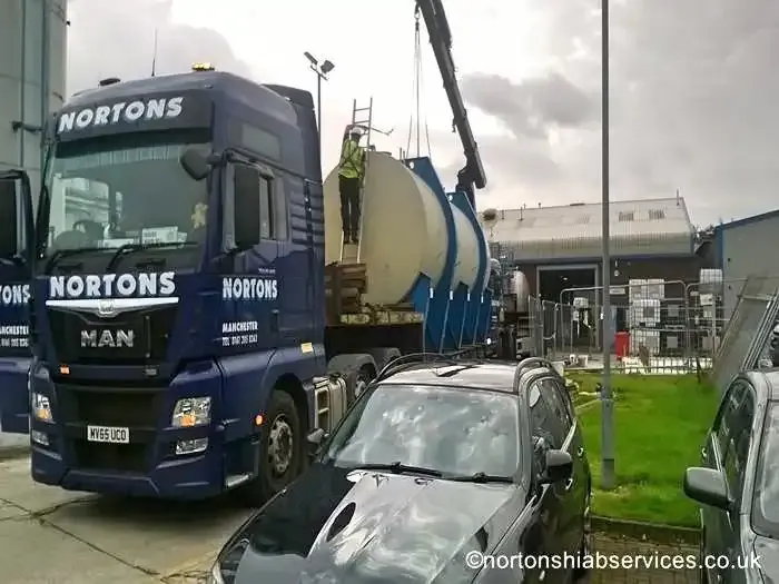 Blue and white process tanks on a Nortons trailer bed at a working plant