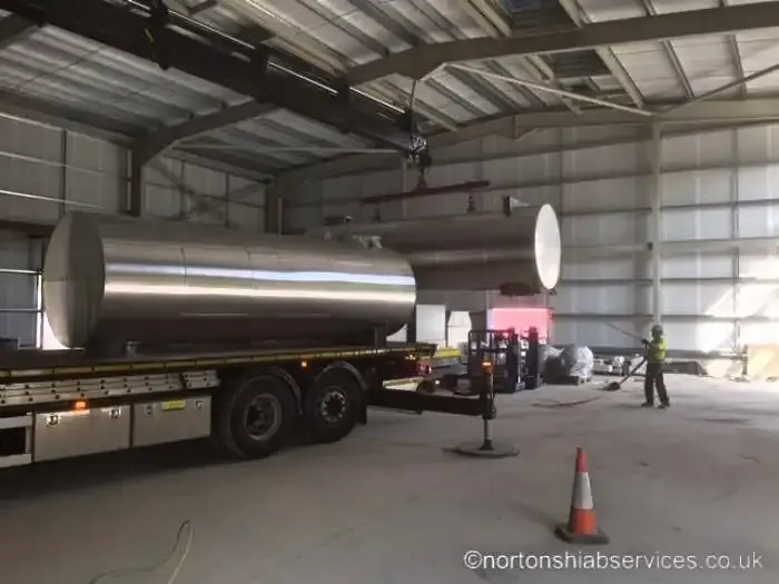 A stainless steel vessel on a Nortons trailer taken inside a building under the roof steels