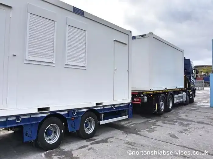 Two white portable cabins loaded on a Nortons rigid and drawbar trailer
