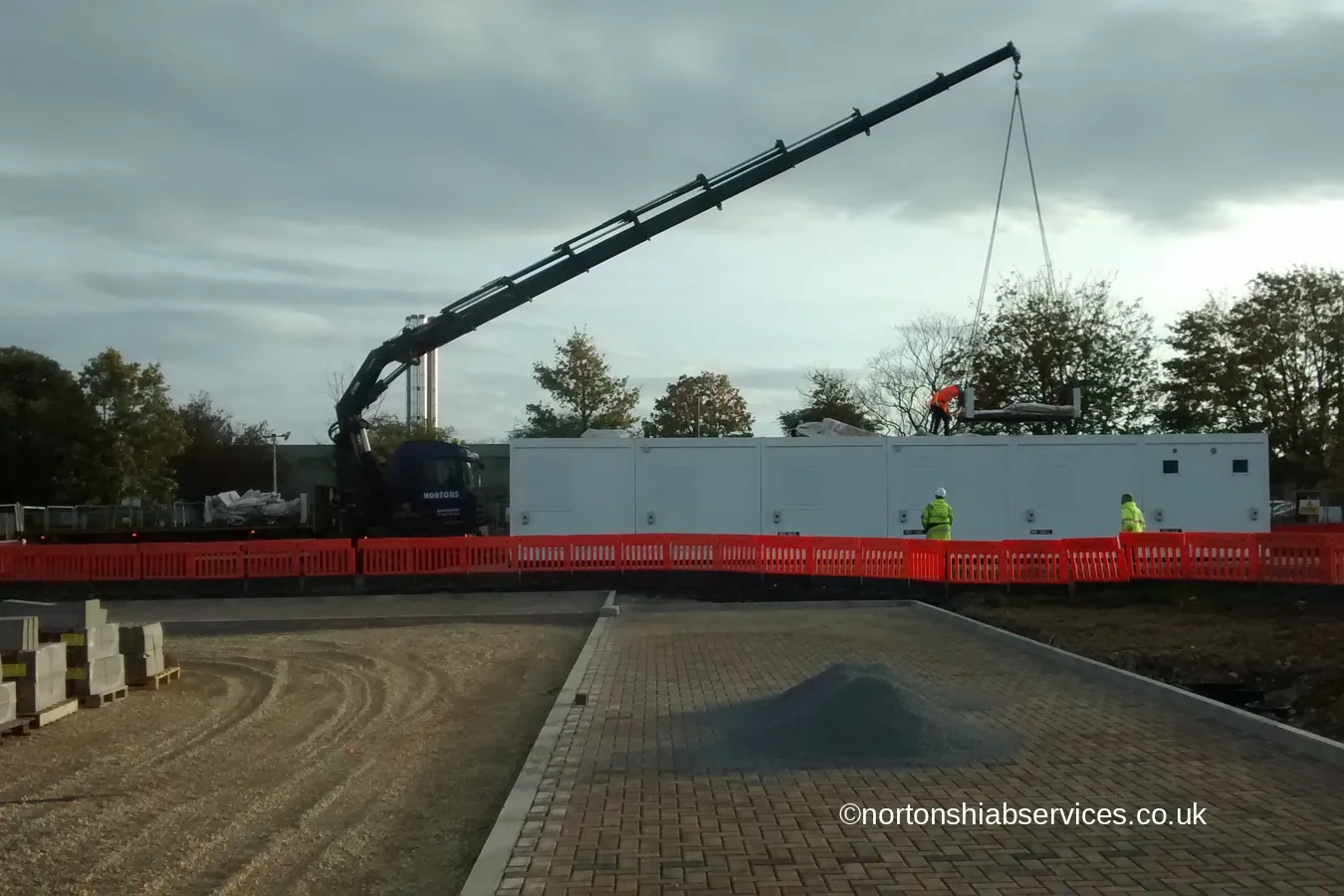 A Nortons hiab with the boom extended placing a long modular unit at a hospital site