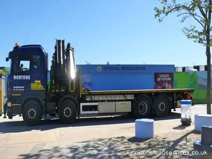 A retail unit loaded on a Nortons flatbed with the crane folded, against a clear sky
