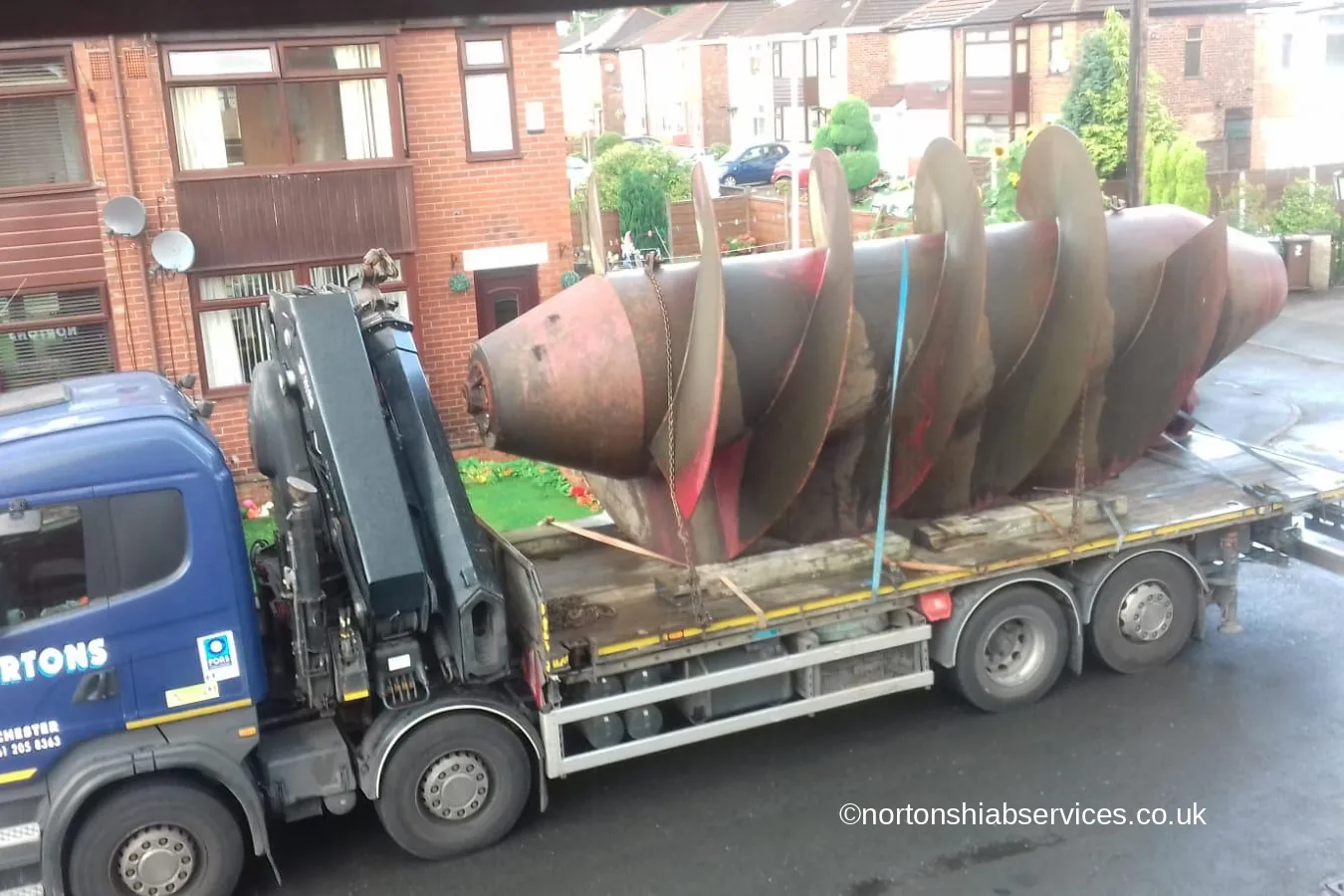A Nortons flatbed carrying an Archimedes screw turbine between terraced houses in the High Peak