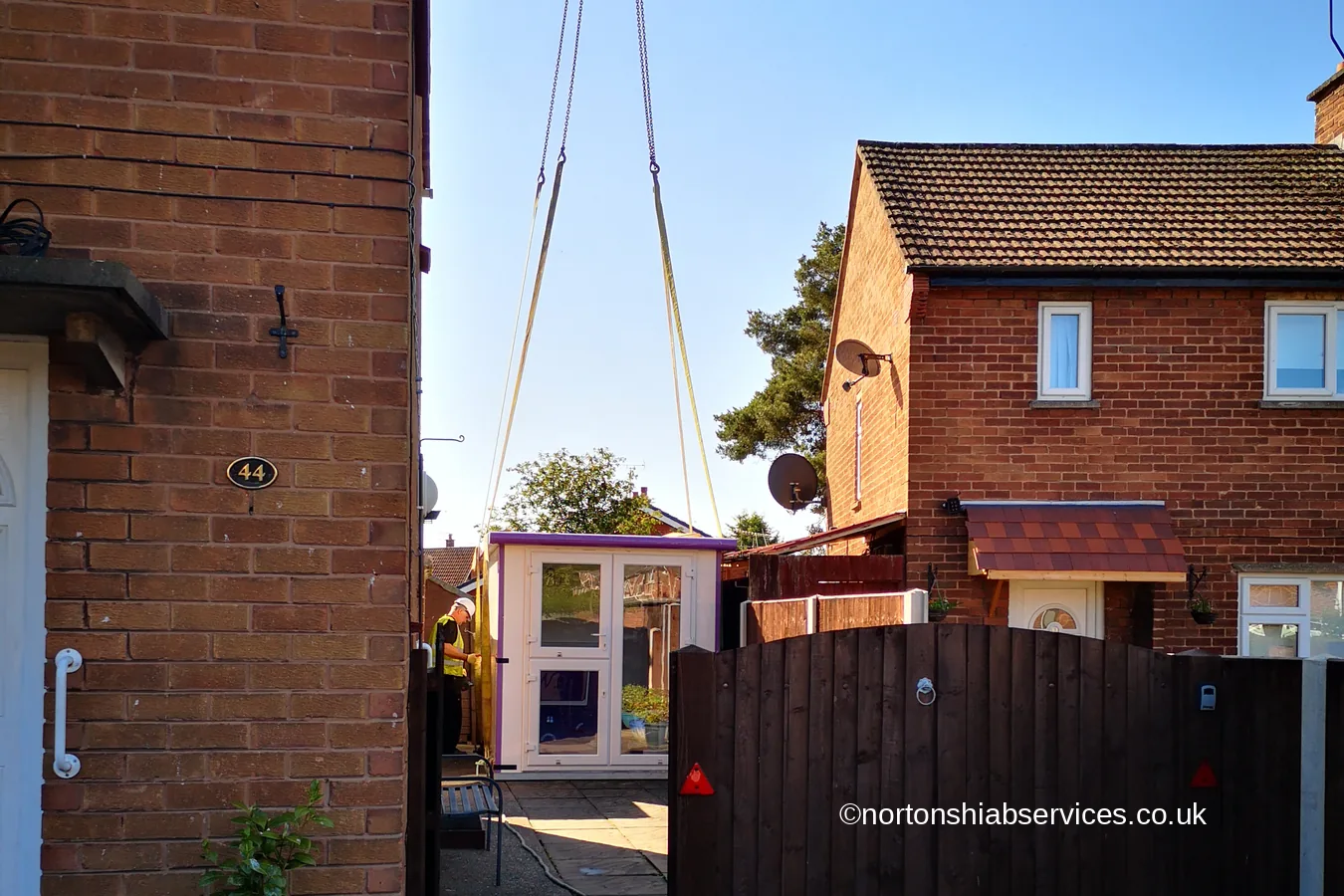 A grooming pod being lowered down the narrow gap between two houses