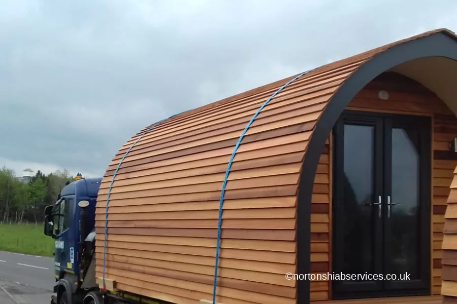 A Nortons hiab lorry carrying a cedar glamping pod on the road north