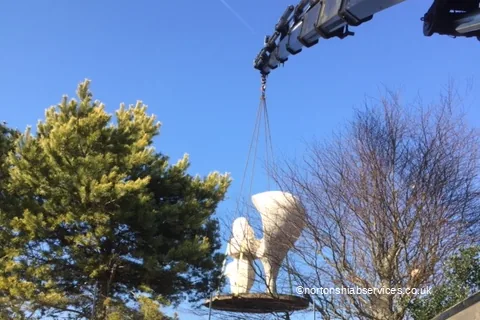 A Nortons lorry crane lifting a carved stone statue on strops at a park in Southport