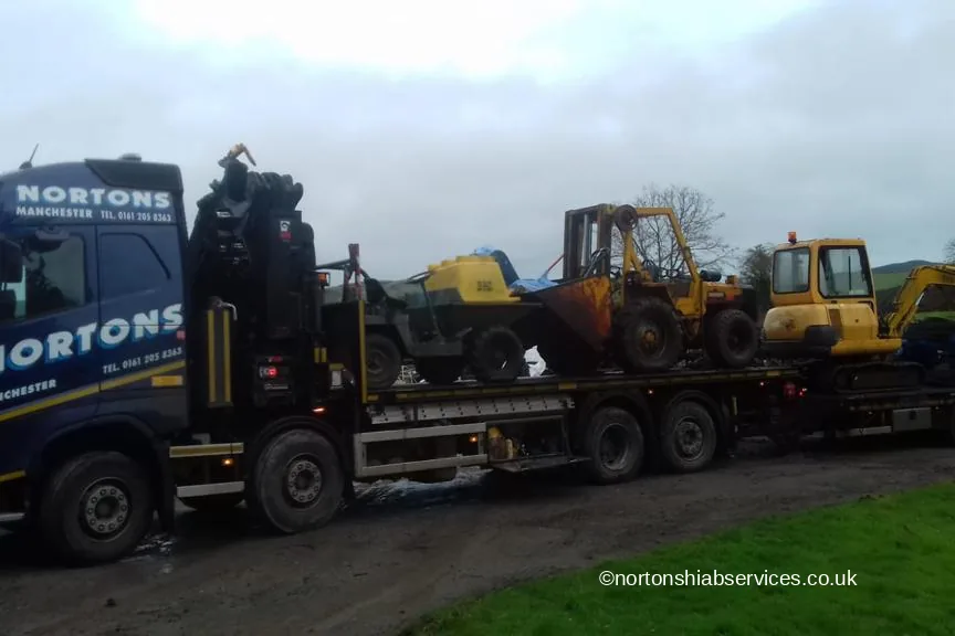 Yellow tracked and wheeled plant machines loaded on a Nortons drawbar trailer for Abergele