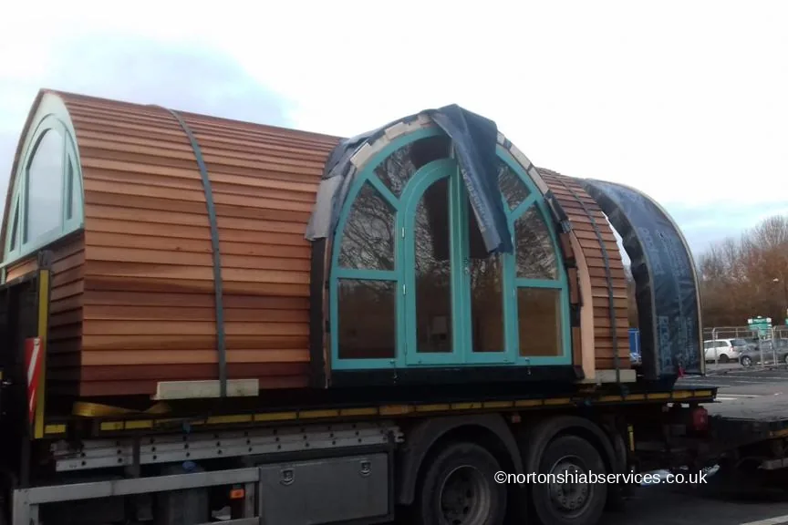 A cedar glamping pod with a glazed arched end loaded on a Nortons trailer for Bicester