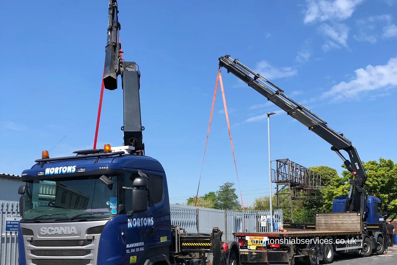 Two Nortons hiab vehicles set up head on for a dual lift of a freezer unit
