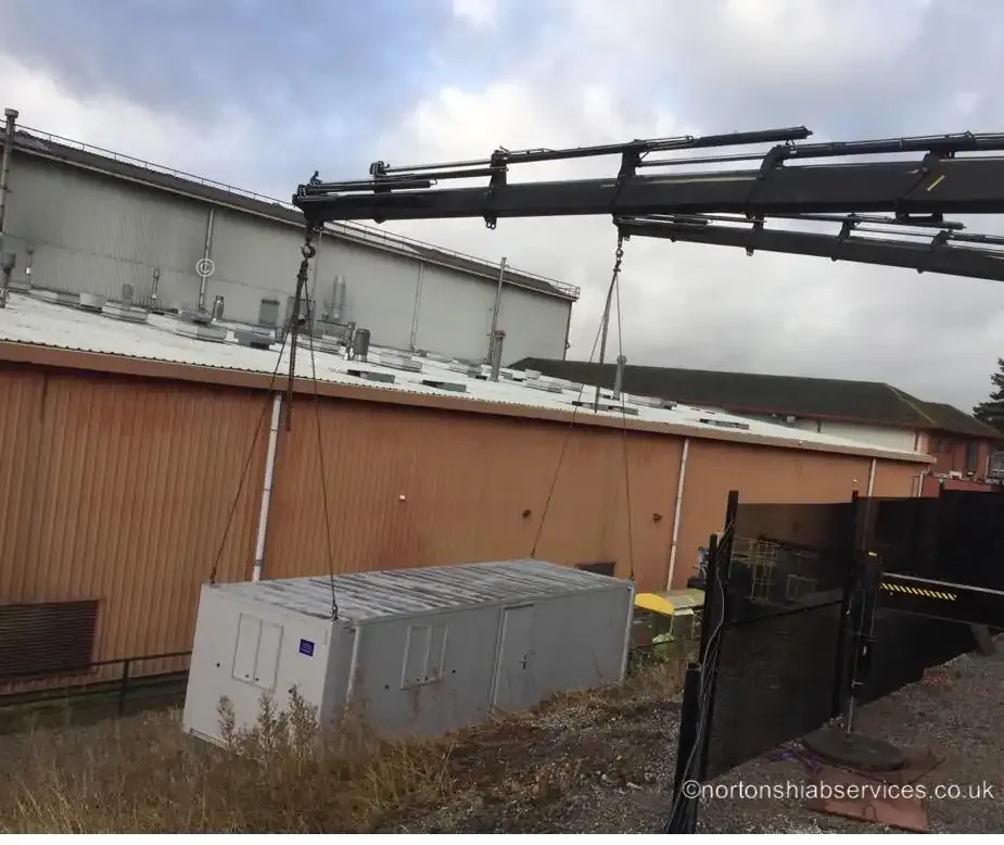 Nortons hiab lowering a container into a space below ground level at Dukinfield