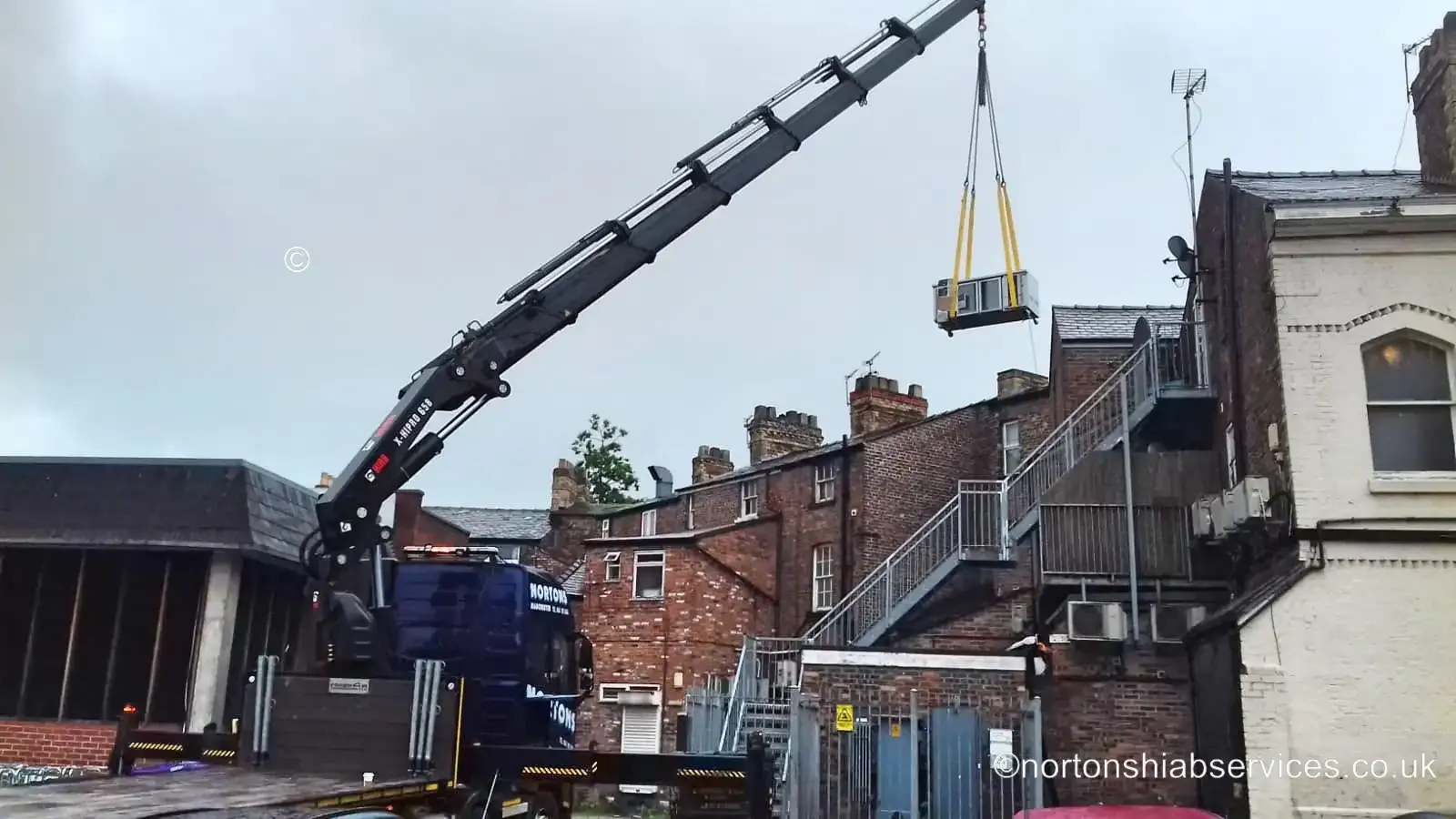 Nortons hiab lifting a large American fridge up to an upper floor opening