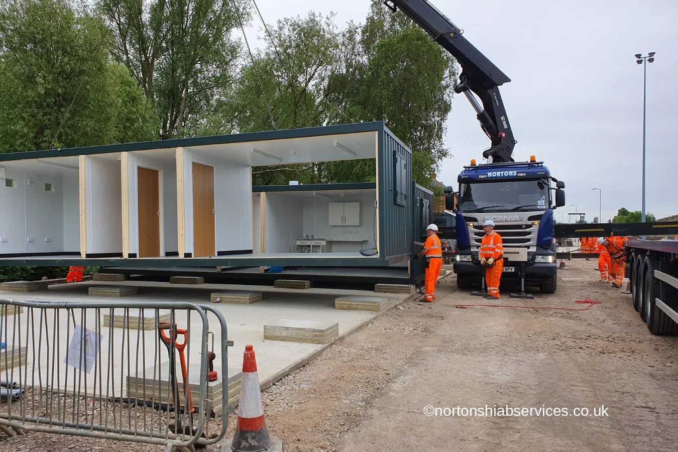 A Nortons crane landing an open fronted modular building on pads at railway sidings in Oxford