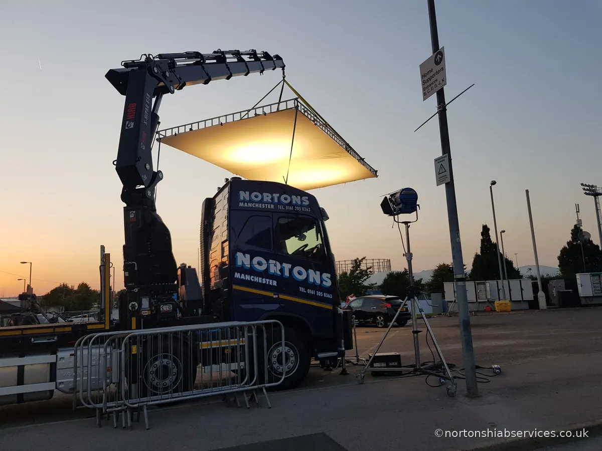 A Nortons hiab holding a large lighting rig for a film unit at dusk in Manchester
