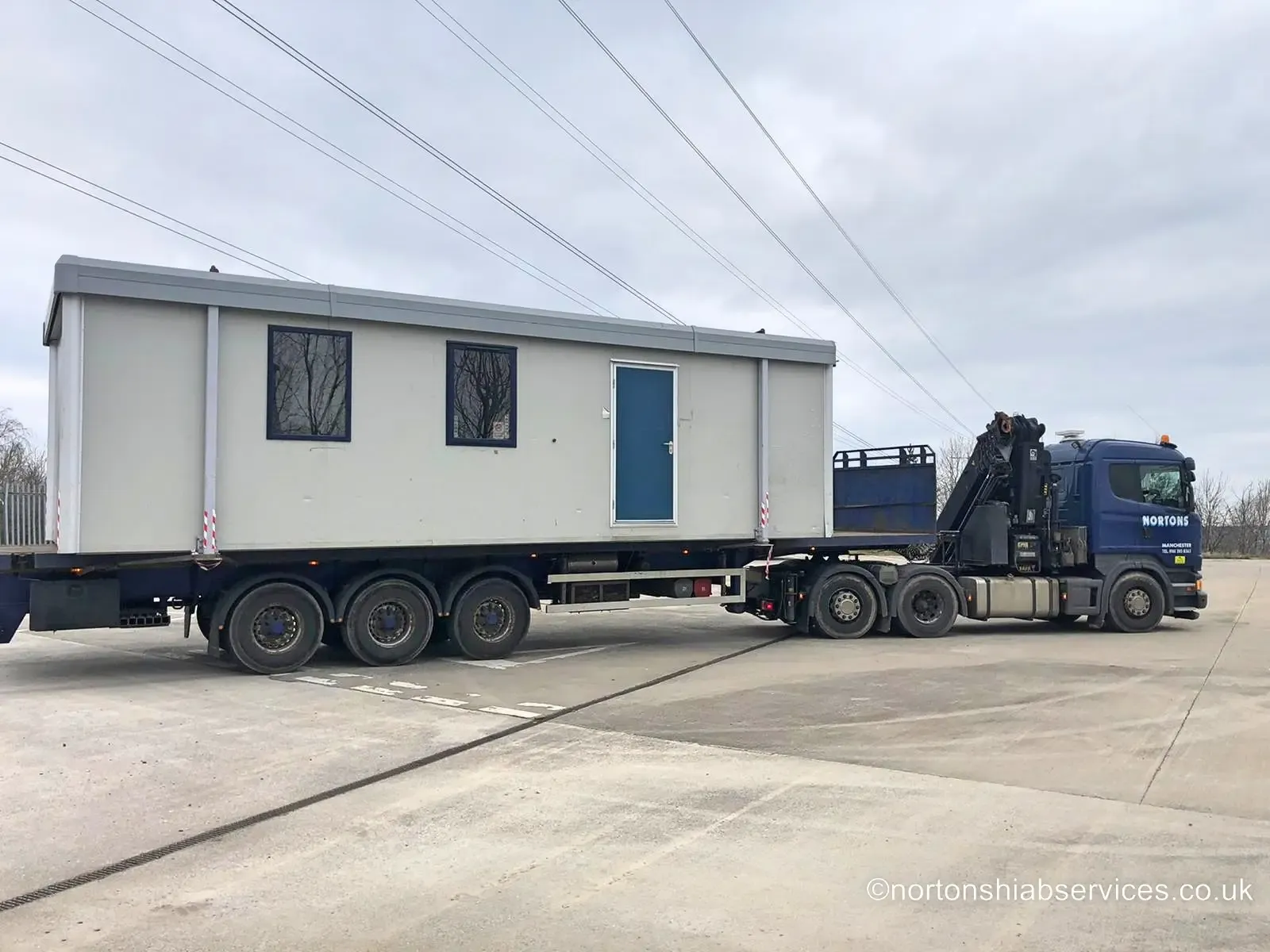 Nortons hiab lifting a portable site cabin off the trailer bed