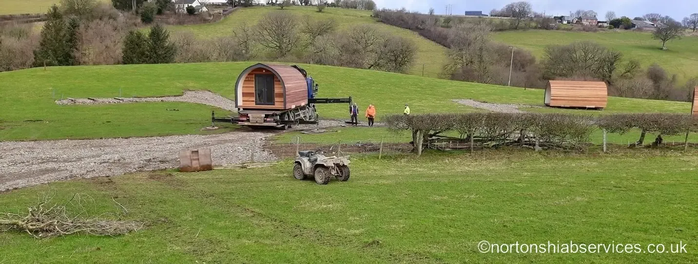 A timber glamping pod set down on its position in an open field