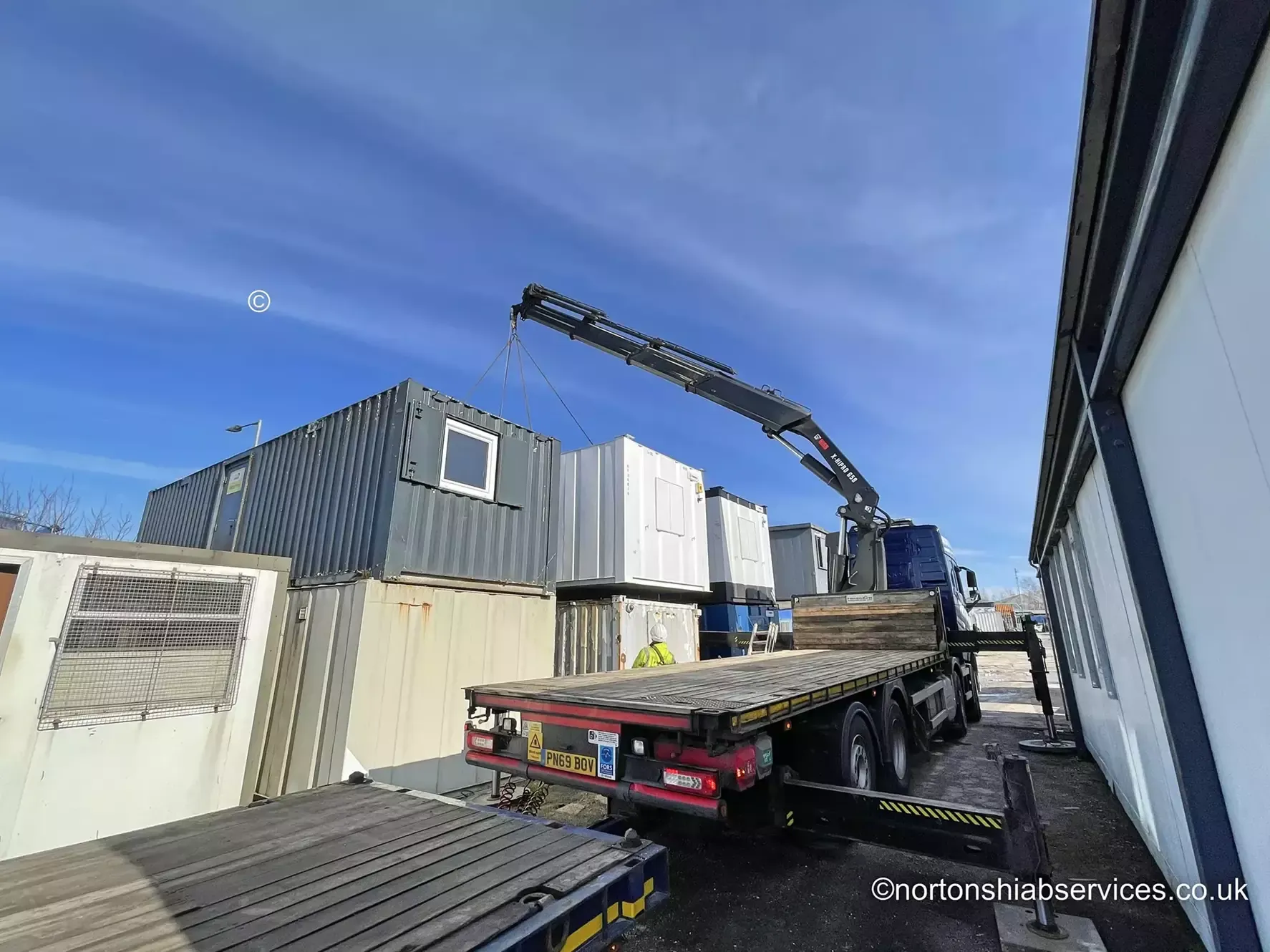 Nortons 658 wagon and drag hiab lifting a portable cabin off the trailer