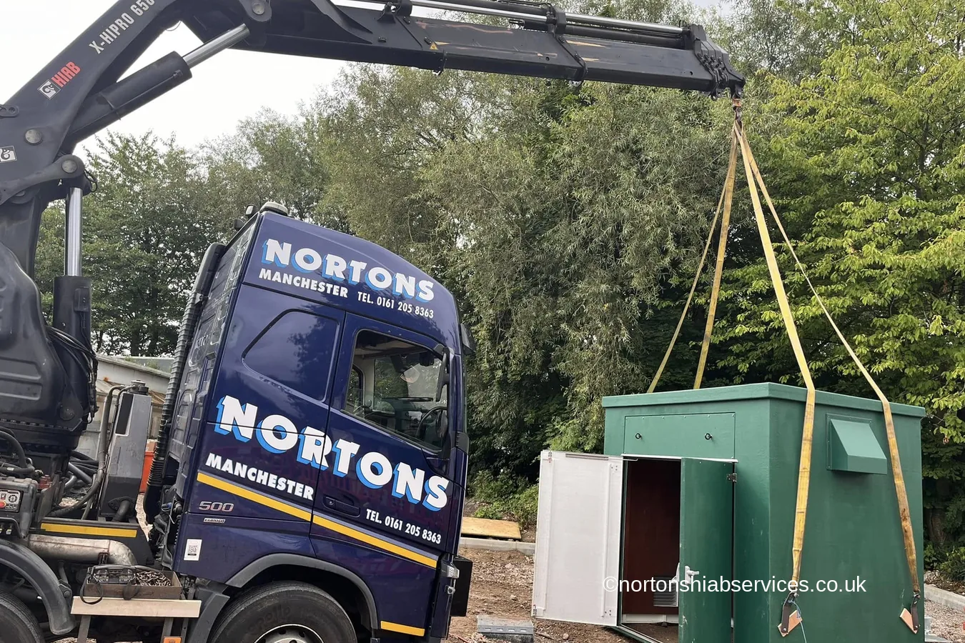 A kiosk building being lowered onto a concrete slab by a Nortons hiab