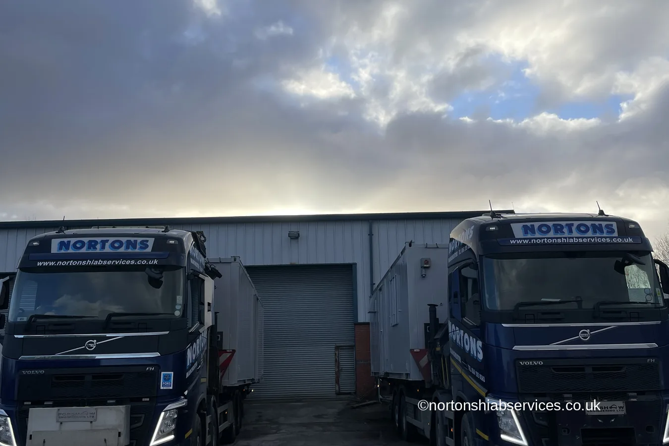 Two Nortons hiab lorries loaded with refurbished cabins in the yard