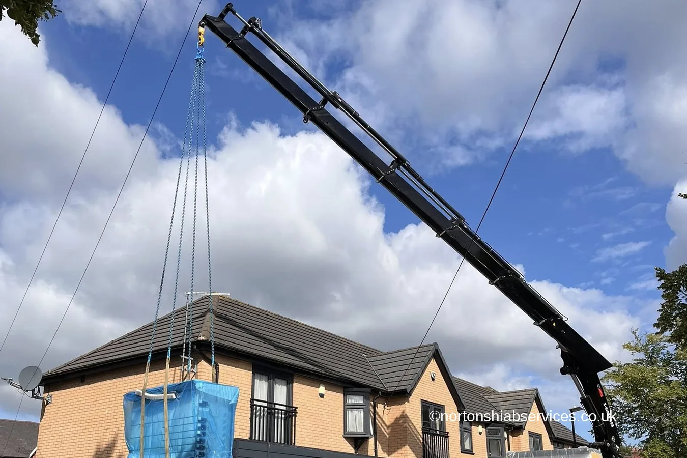 A Nortons hiab lifting wrapped panels over a building in Birmingham