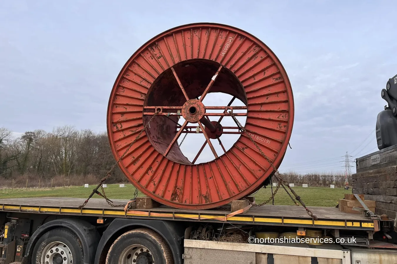 A large red cable drum loaded on a Nortons hiab lorry
