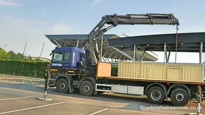 Nortons eight wheeler loaded with a container beside the academy roofline