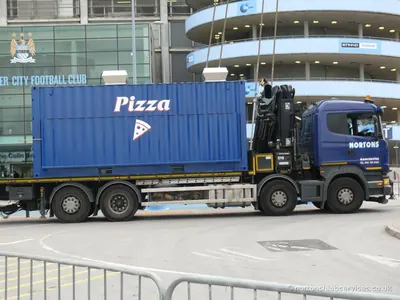 Blue container kiosk on a Nortons vehicle outside a Manchester stadium