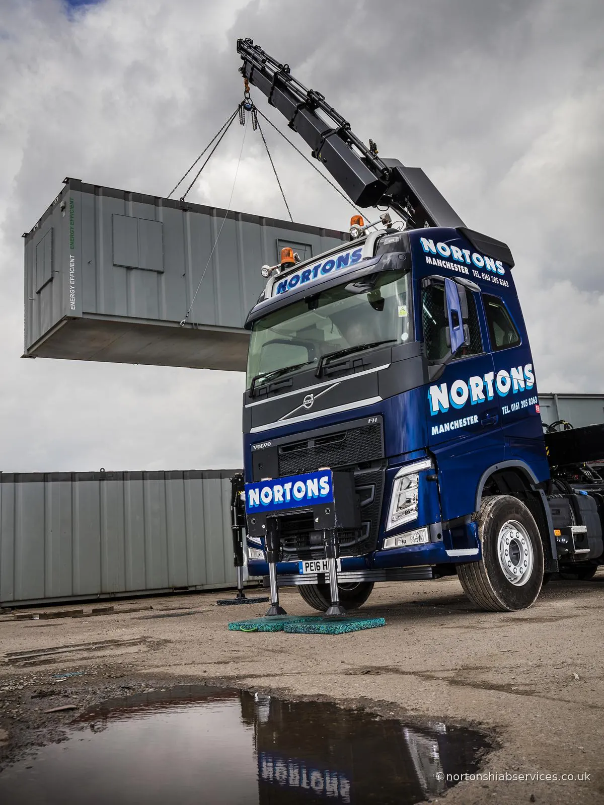 Nortons Volvo hiab down on its outriggers lifting a site cabin off the trailer