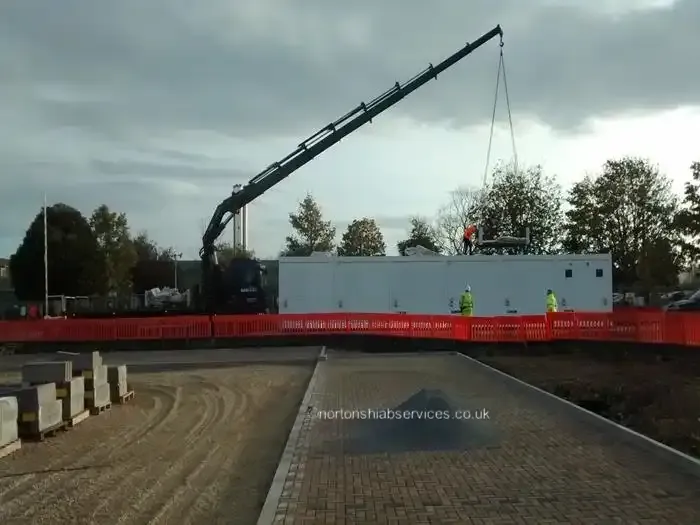 Nortons hiab reaching in over a barrier line to place a large unit