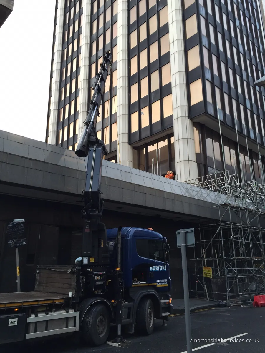 Load being lowered onto a Nortons hiab lorry in a city street