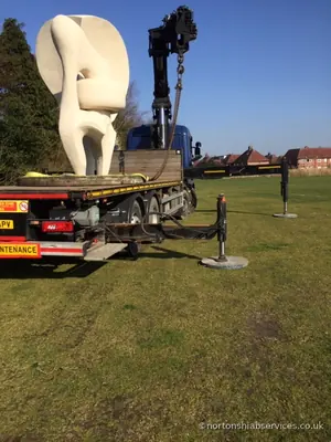 A Nortons rigid with its stabiliser legs down on grass beside the white cast sculpture on its deck