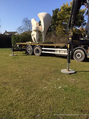 A large white cast sculpture standing on the deck of a Nortons rigid parked on a green
