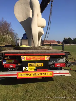 The white cast sculpture slung from the crane above the rear of a Nortons lorry deck