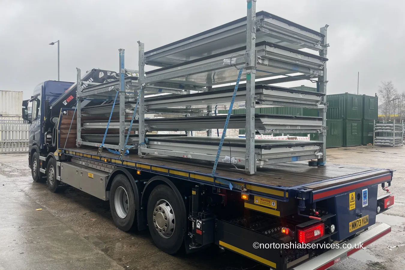 Galvanised stillage racks strapped down on the bed of a Nortons rigid in a works yard