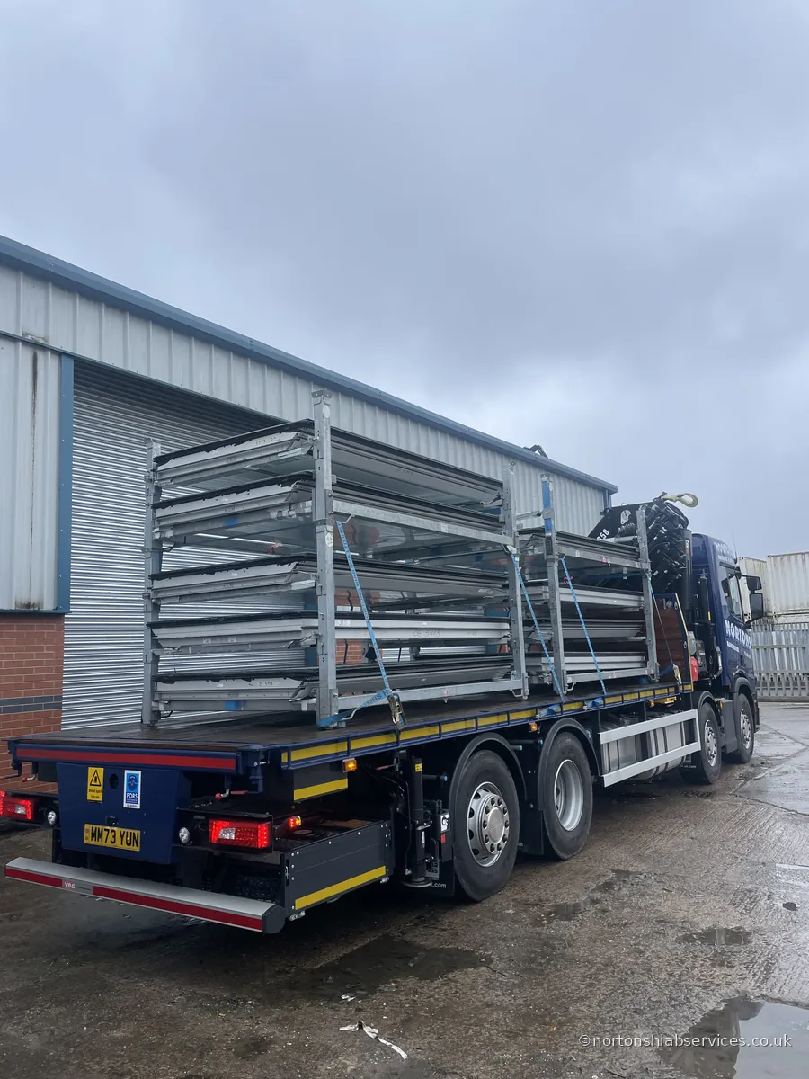 A Nortons eight-wheel rigid loaded with tall galvanised stillage racks, strapped and ready to leave an industrial unit