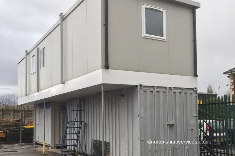 A two storey site office set up over a shipping container in Bolton with an access stair to the upper floor