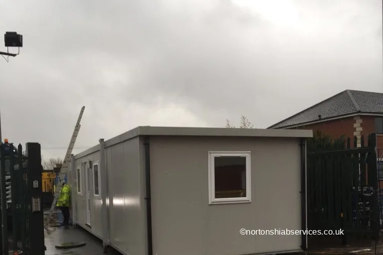 A site office set down at the gate of a yard in Bolton with the crane boom still behind it