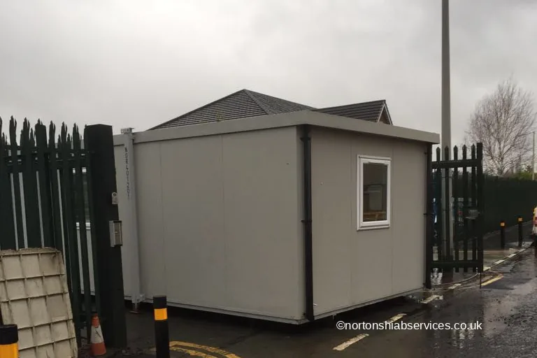 A single office unit standing on the hard standing inside a gated yard in Bolton