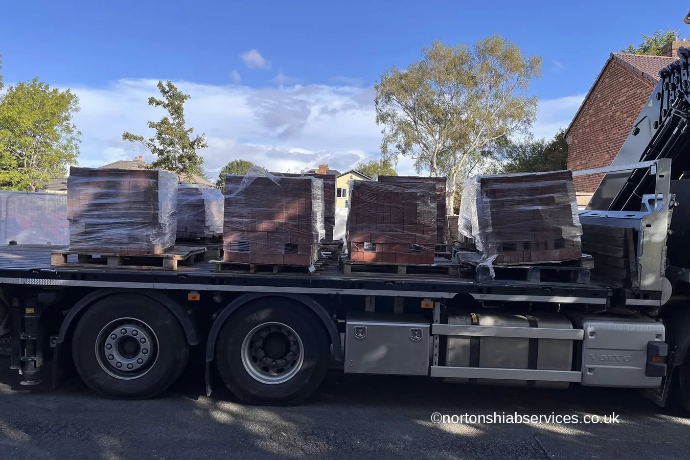 A Nortons crane lorry loaded with pallets of bricks on a residential street at Ellesmere Port in Cheshire
