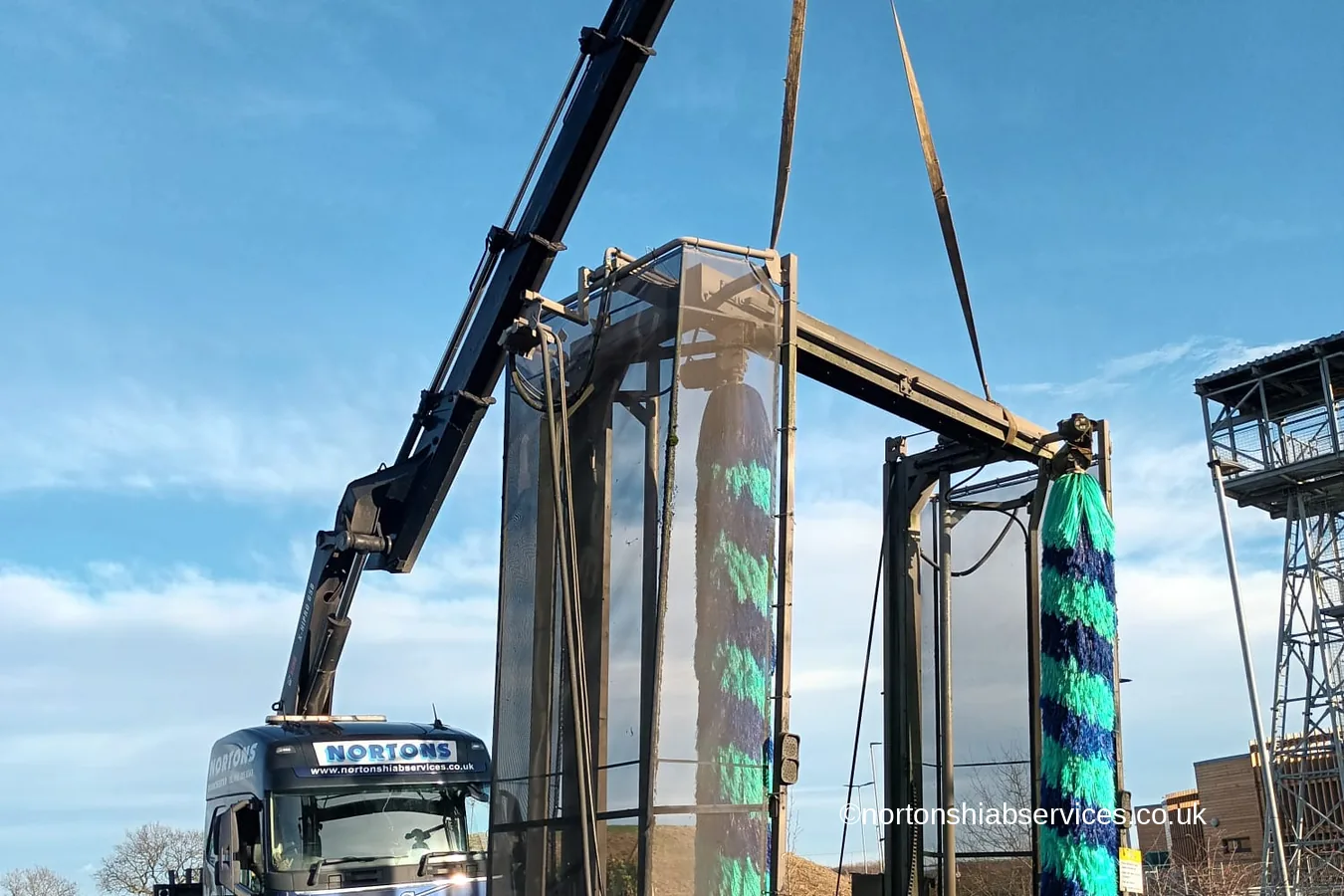 A Nortons crane lorry lifting a commercial truck wash gantry clear of the ground at Lymm in Cheshire