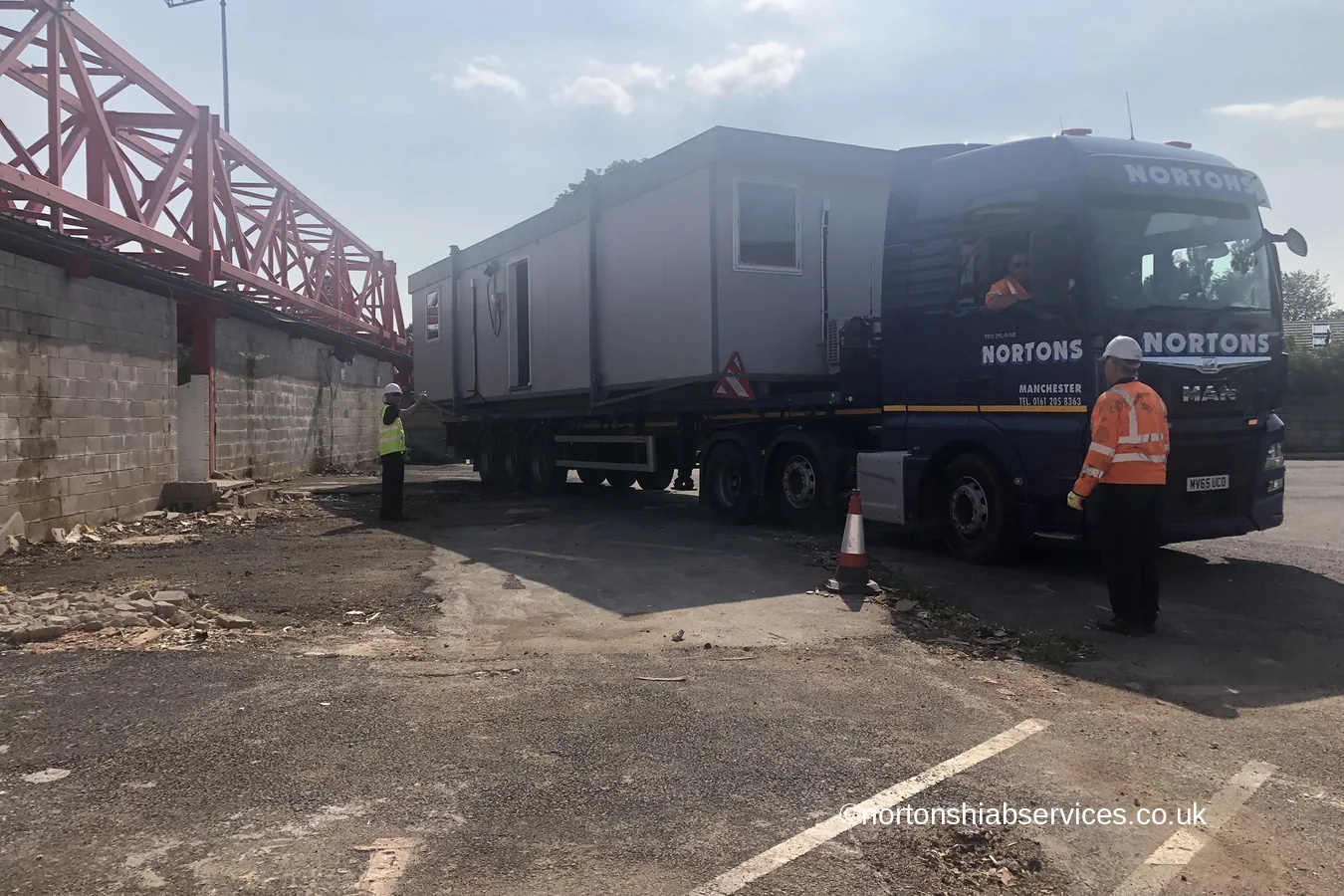 A Nortons artic carrying a site cabin along the back of a football ground at Accrington in east Lancashire