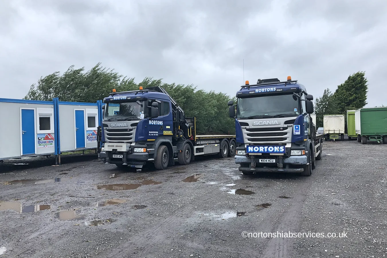 Two Nortons crane lorries standing alongside a line of delivered accommodation cabins at Hesketh Bank