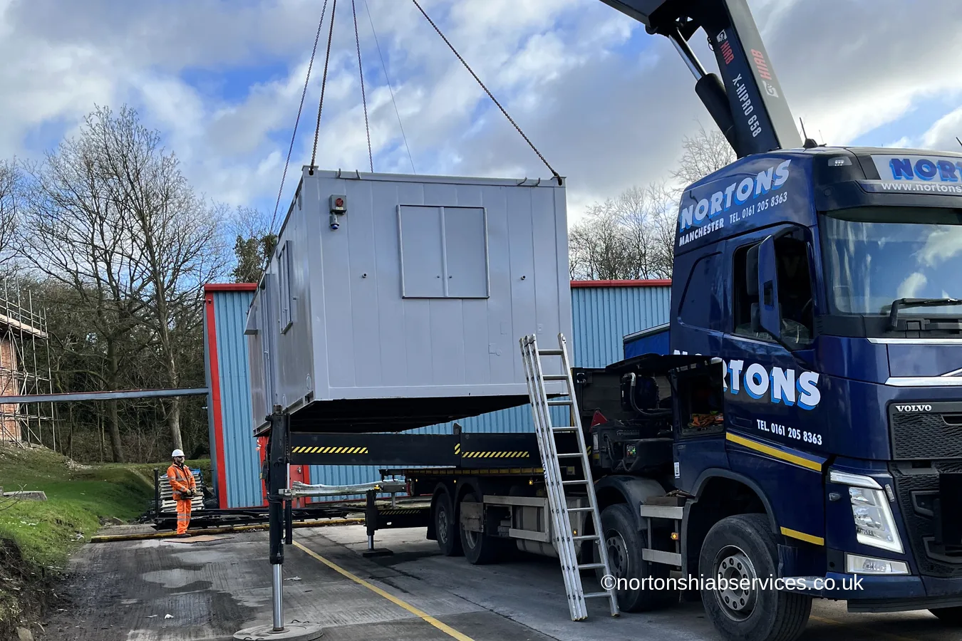 A refurbished cabin lifted off the bed of a Nortons lorry in a sloping yard at Romiley