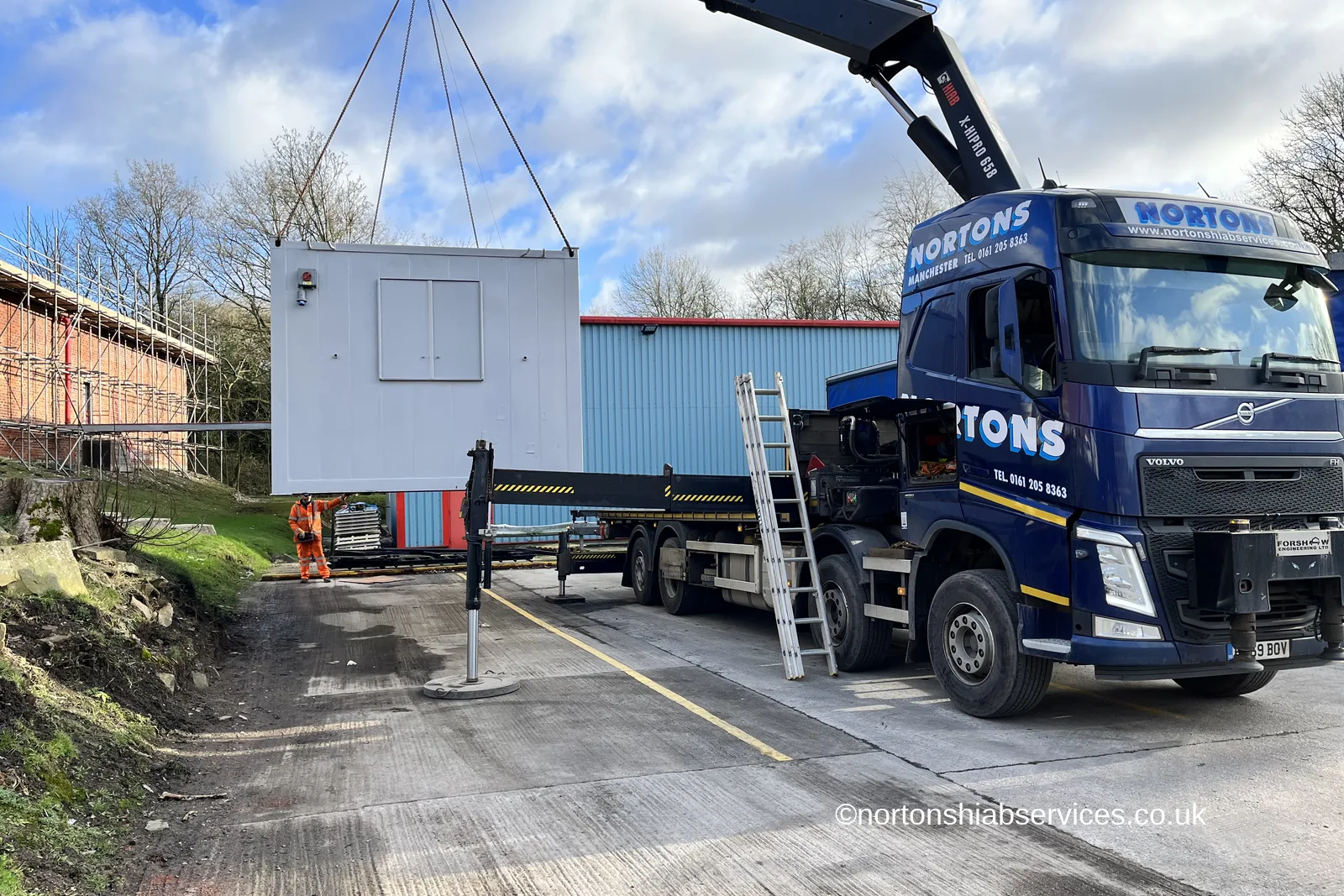 A Nortons crane lorry holding a refurbished site cabin on four slings in the yard at Romiley Board Mill in Stockport