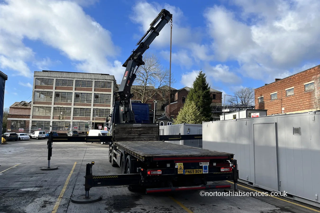 A Nortons crane lorry working in front of the multi storey brick mill building at Romiley in Stockport