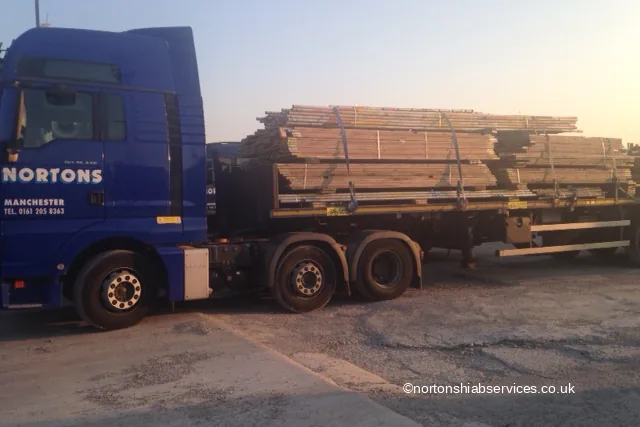 A Nortons tractor unit and trailer loaded with scaffold boards and timber at first light