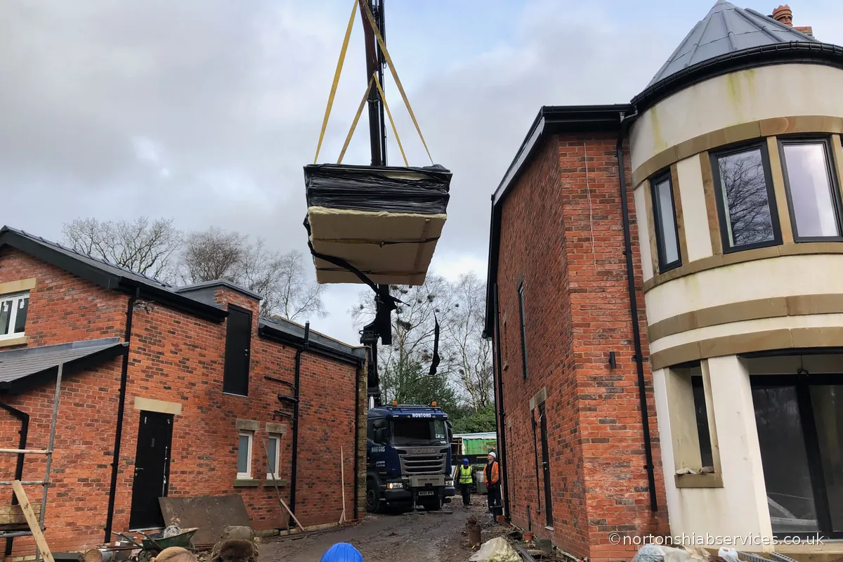 A Nortons 855 hiab lifting a 14ft wide medical pool through the gap between two new build houses at Wigan